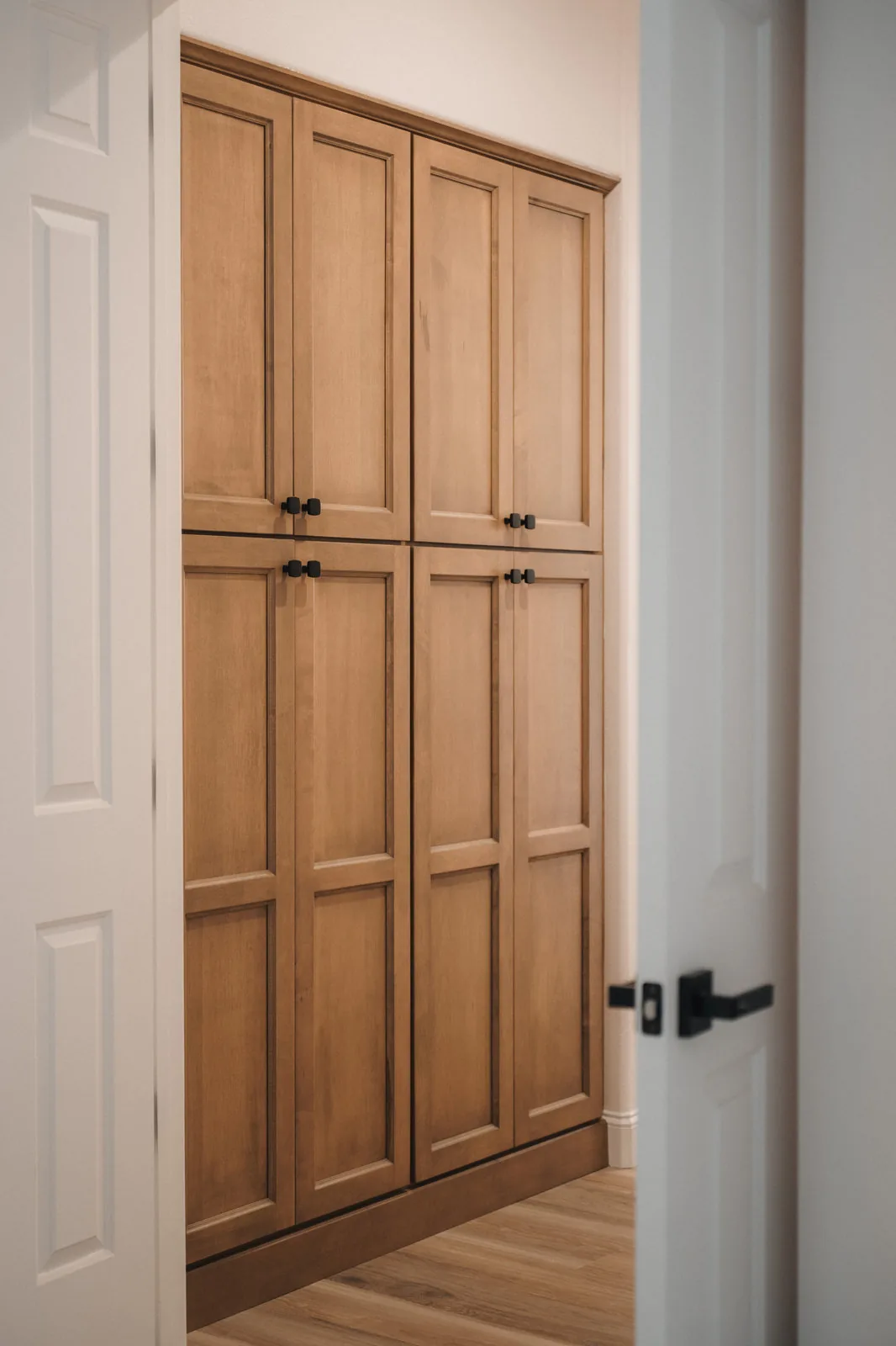 Tall natural wood cabinet doors with matte black pulls