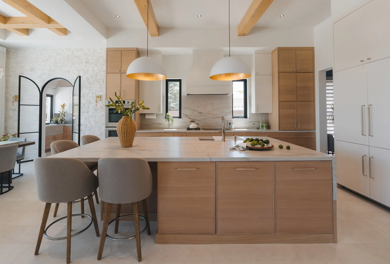 Newly built kitchen with a long oak island, upholstered stools and beamed ceiling