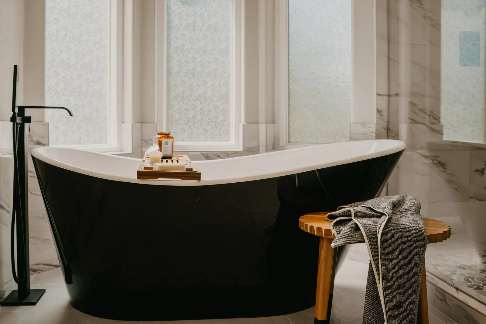 Marble bathroom with a black clawfoot tub and a glass shower
