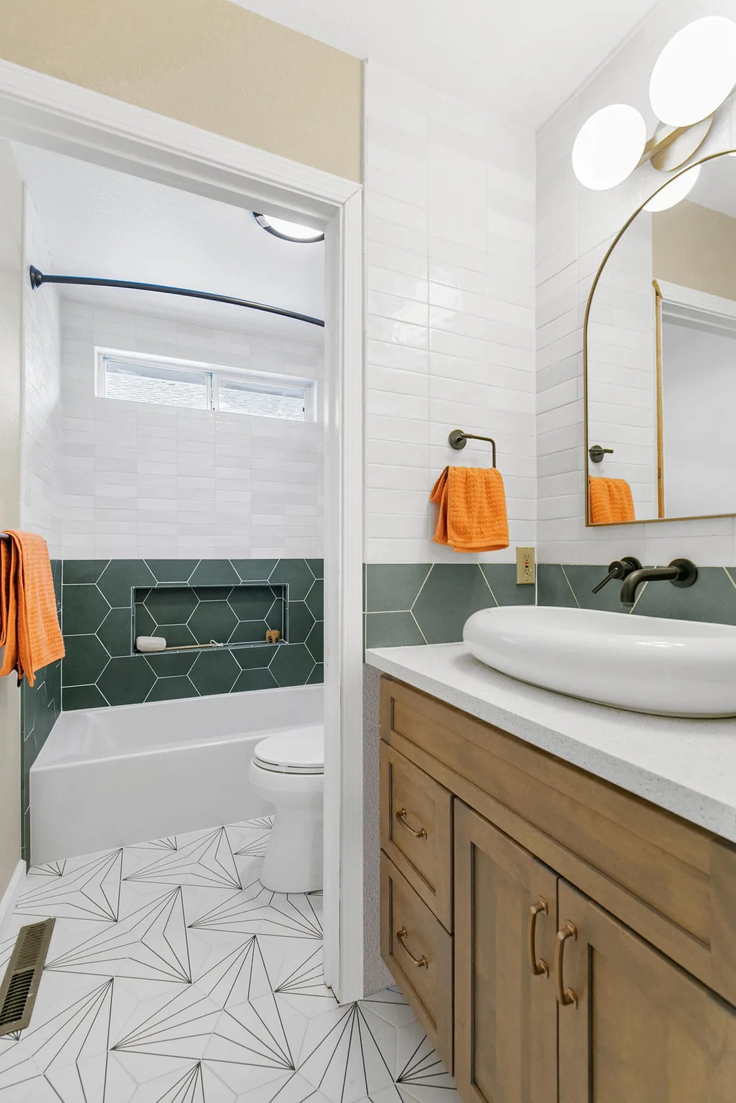 Guest bath with green tile wainscot, an oak vanity and a patterned floor
