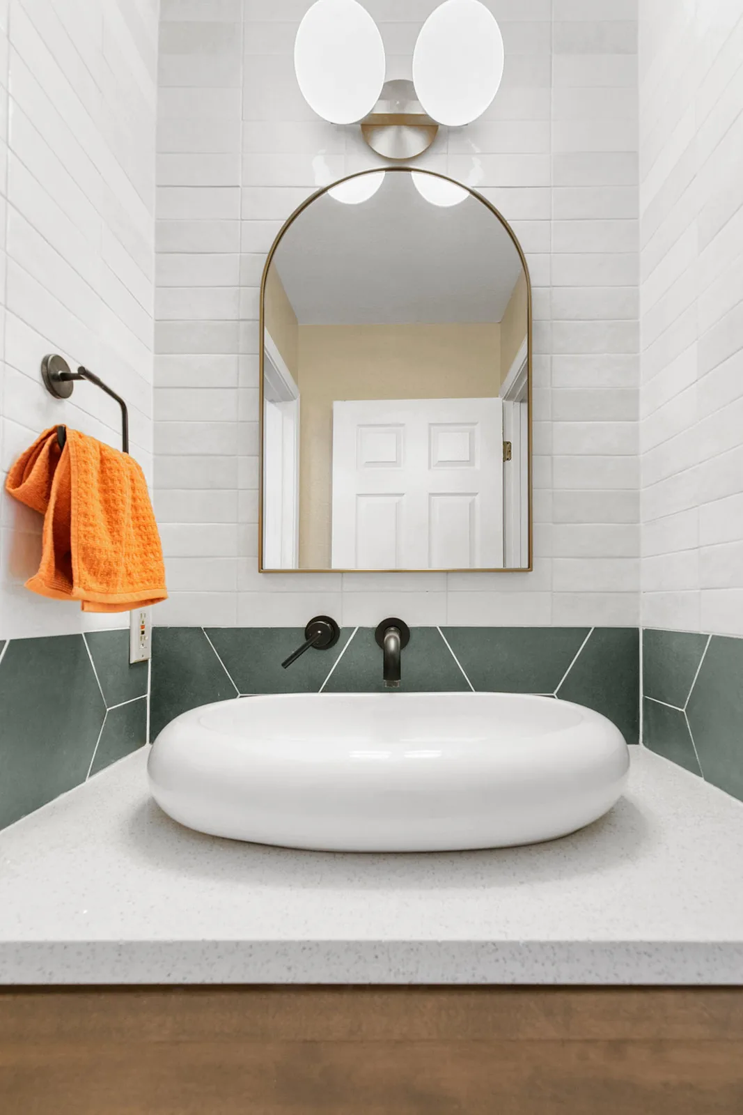 Vessel sink on an oak vanity against a green tile wall