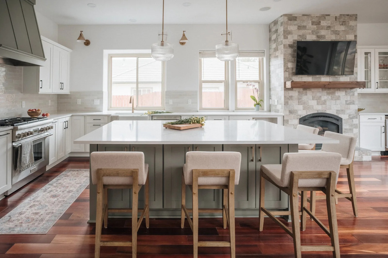 Bright kitchen with a long island, cane stools and a wall of white cabinetry