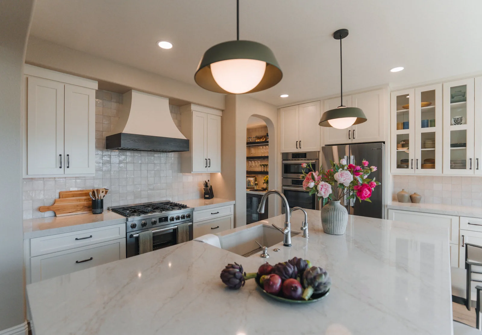 White kitchen with a wide quartz island and a pantry beyond