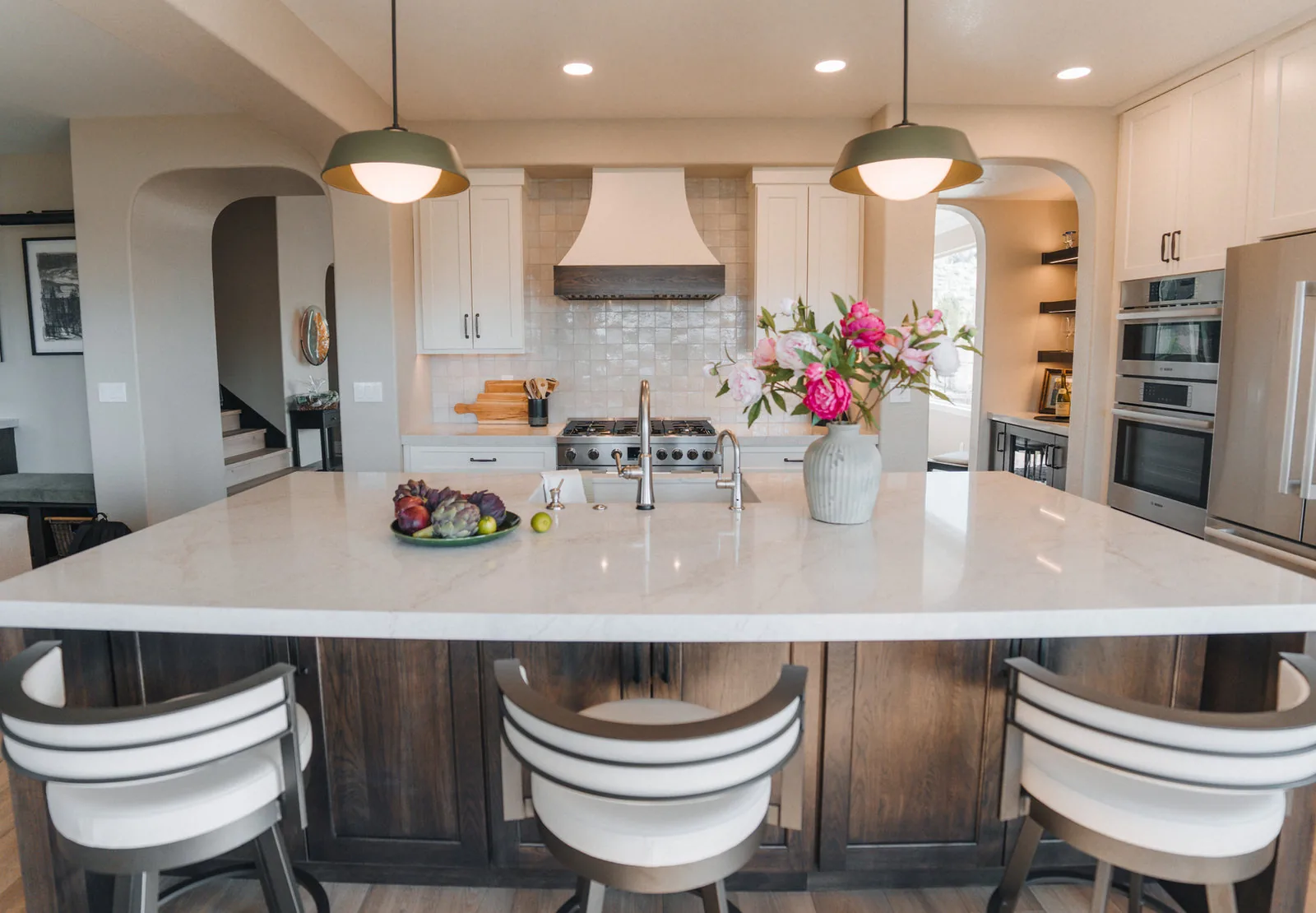 Kitchen with a large island, arched pantry opening and a plaster hood